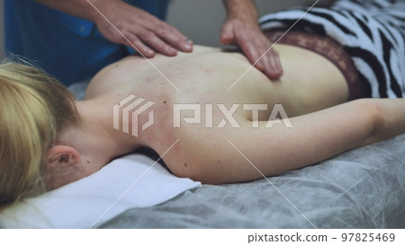 A masseur massages a girl's back. 97825469