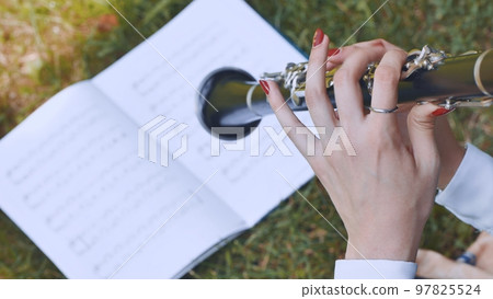 The girl plays the clarinet by notes. 97825524
