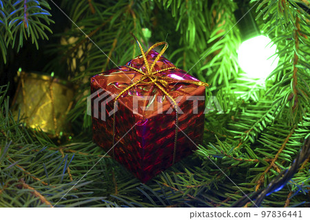 Christmas gift on the background of the Christmas tree close-up Christmas gift on the background of the Christmas tree close-up 97836441