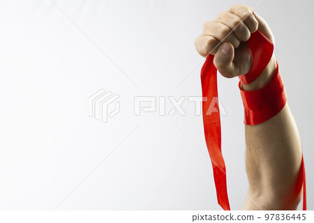 Health care and medicine concept. AIDS awareness. Male hand with a clenched fist red AIDS awareness ribbon on white background. International AIDS Day 97836445