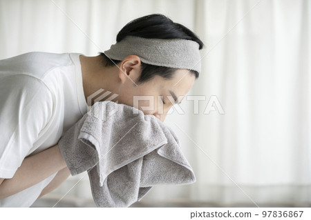 A young man wiping his face with a towel face wash image A young man wiping his face with a towel face wash image 97836867