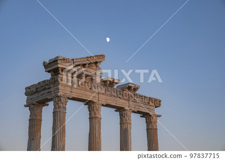 Low angle view of old ruins of Roman Temple of Apollo with moon in clear blue sky in the background at dusk in Side, Turkey 97837715