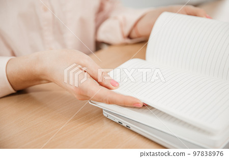Close-up of woman's hands at work, she write the plan of the day in a notebook at her workplace. Work, learning, student and home office concept Close-up of woman's hands at work, she write the plan of the day in a notebook at her workplace. Work, learning, student and home office concept 97838976