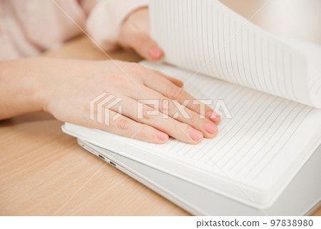 Close-up of woman's hands at work, she write the plan of the day in a notebook at her workplace. Work, learning, student and home office concept Close-up of woman's hands at work, she write the plan of the day in a notebook at her workplace. Work, learning, student and home office concept 97838980