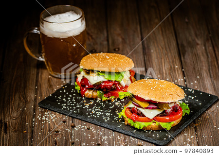 From above shot of homemade beef burgers on stone board with pin of beer. Selective focus.  97840893