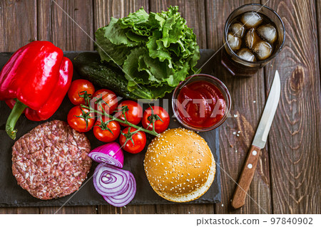 From above shot of process of making burger with vegetables, bun and artificial meat on board From above shot of process of making burger with vegetables, bun and artificial meat on board 97840902