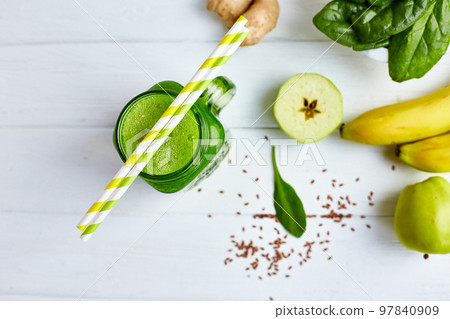 From above view of jar mug filled with green smoothie and ingredients on wooden table. Healthy food From above view of jar mug filled with green smoothie and ingredients on wooden table. Healthy food 97840909