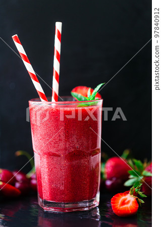 Front view of berry juice or smoothie with fresh strawberries and cherries on dark background. Front view of berry juice or smoothie with fresh strawberries and cherries on dark background. 97840912