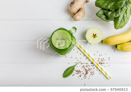 Top view of jar mug filled with green smoothie and ingredients on wooden table. Vegetarian food  97840915