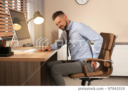 Man suffering from hemorrhoid at workplace in office 97842010