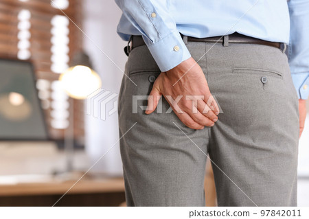 Man suffering from hemorrhoid in office, closeup Man suffering from hemorrhoid in office, closeup 97842011