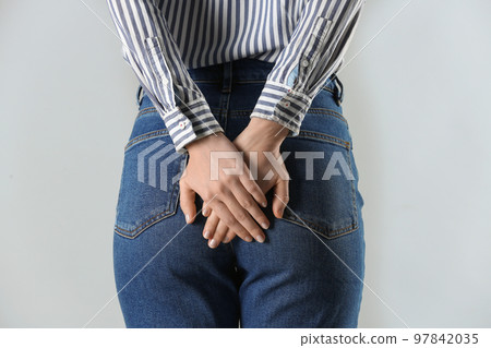 Woman suffering from hemorrhoid on light grey background, closeup 97842035