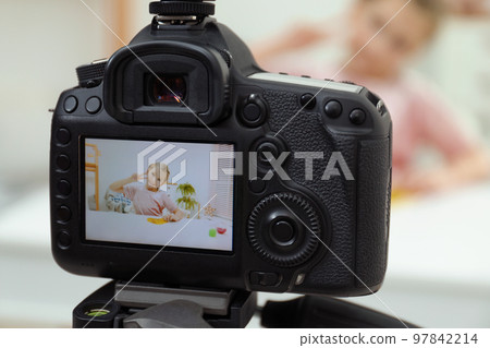 Cute little blogger with slime recording video at home, focus on camera 97842214