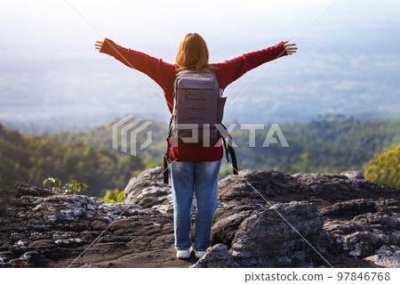 Young woman on top of the mountain with the arms raised enjoying freedom, winner and success concept. Young woman on top of the mountain with the arms raised enjoying freedom, winner and success concept. 97846768