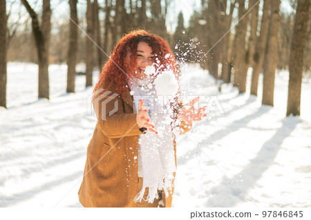 Fat caucasian woman playing snowballs in the park.  97846845