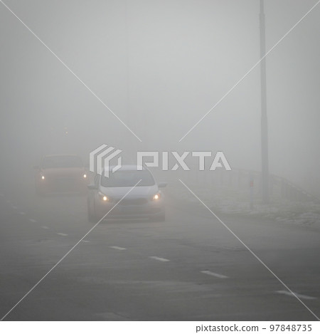 Bad weather driving - foggy hazy country road. Motorway - road traffic. Winter time. 97848735