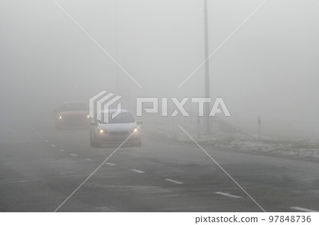 Cars in the fog. Bad winter weather and dangerous automobile traffic on the road. Light vehicles in fog. 97848736