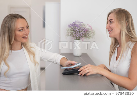 A woman pays using a non -contact payment of the NFC used by a smartphone. A woman pays using a non -contact payment of the NFC used by a smartphone. 97848830