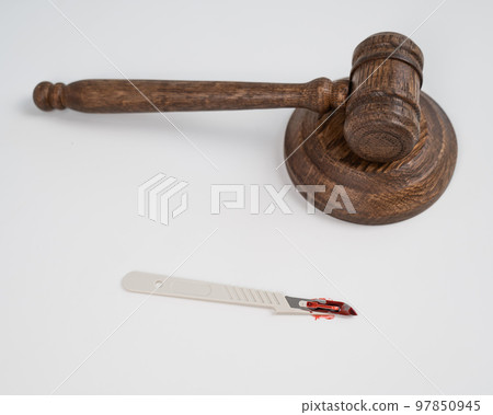 A scalpel covered in blood and a judge's wooden gavel. A scalpel covered in blood and a judge's wooden gavel. 97850945