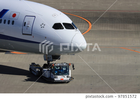 Airliner being towed by a towing tractor 97851572