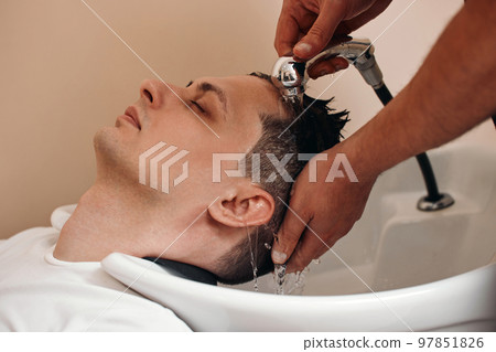 Barber washing hair of caucasian man , close-up Barber washing hair of caucasian man , close-up 97851826