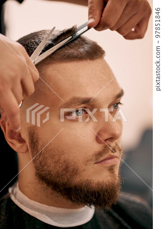 hairdresser does hairstyle with scissors in barber shop 97851846