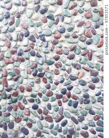 Vertical background image of a wall filled with turquoise, brown, black and white pebbles in strong sunlight 97853571