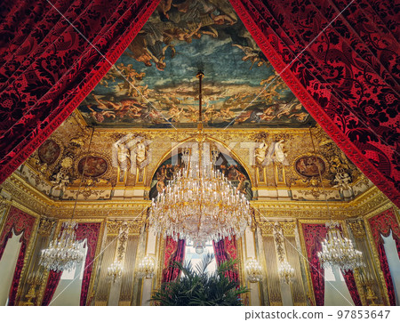 Beautiful decorated Napoleon apartments at Louvre palace. Royal family rooms with cardinal red curtains, golden ornate walls, paintings and crystal chandeliers suspended from ceiling Beautiful decorated Napoleon apartments at Louvre palace. Royal family rooms with cardinal red curtains, golden ornate walls, paintings and crystal chandeliers suspended from ceiling 97853647