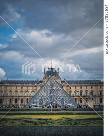 Outdoors view to the Louvre Museum in Paris, France. The historical palace building with the modern glass pyramid in center, vertical background 97853654