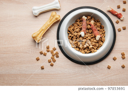 A bowl of dog food on a wooden floor. A bowl of dog food on a wooden floor. 97853691