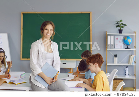 Portrait of beautiful smiling female teacher in school classroom on background of schoolchildren. Portrait of beautiful smiling female teacher in school classroom on background of schoolchildren. 97854153