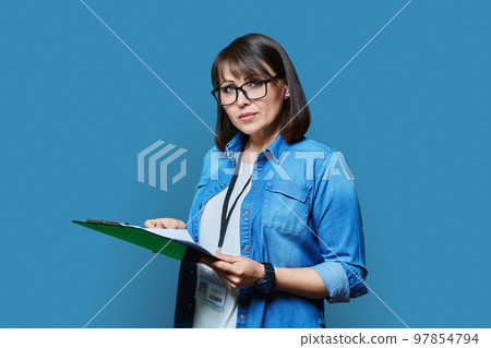 Portrait of woman worker with industrial center card clipboard, on blue background Portrait of woman worker with industrial center card clipboard, on blue background 97854794