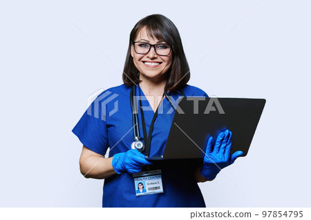 Friendly female doctor with laptop looking at camera on white background Friendly female doctor with laptop looking at camera on white background 97854795