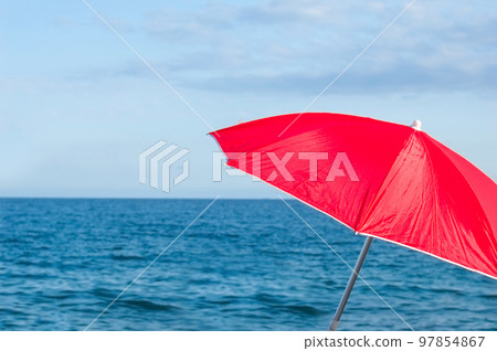Red parasol umbrella on tropical island beach. Colourful sunshade in the beach on sunny summer day. Holiday relaxation with turquoise sea and blue sky landscape. Summer vacation concept 97854867