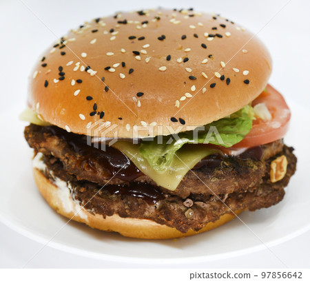 Double meat burger with vegetables on a white background. Delicious cheeseburger on a plate. Meat fast food. A large hamburger with a double cutlet. 97856642