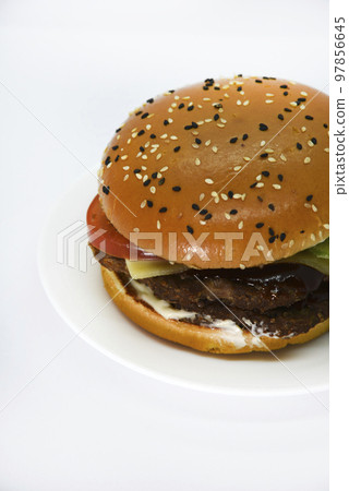 Double meat burger with vegetables on a white background. Delicious cheeseburger on a plate. Meat fast food. A large hamburger with a double cutlet. 97856645