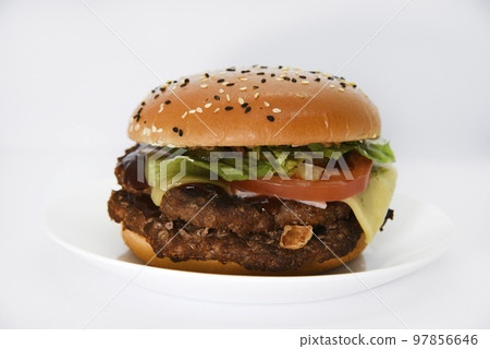 Double meat burger with vegetables on a white background. Delicious cheeseburger on a plate. Meat fast food. A large hamburger with a double cutlet. 97856646