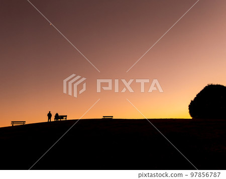 The silhouettes of people and hills strolling in the twilight time of winter 97856787