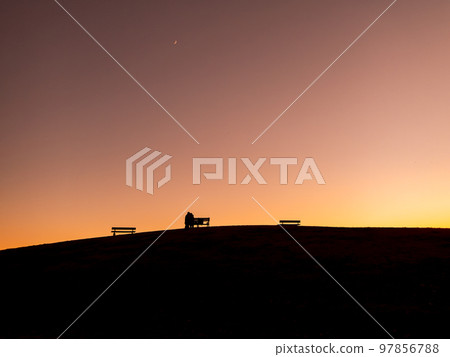 The silhouettes of people and hills strolling in the twilight time of winter 97856788