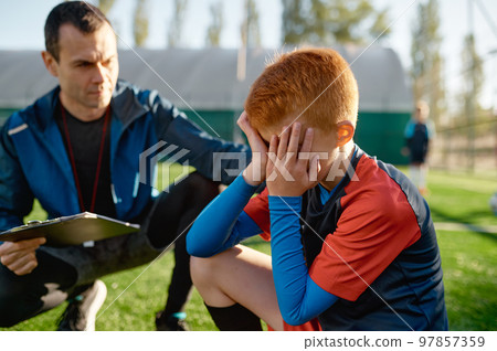 Coach comforting crying little soccer player after missed goal 97857359