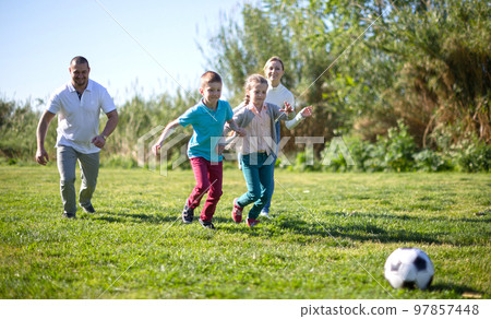 Children and parents run to the soccer sword in the summer in the park Children and parents run to the soccer sword in the summer in the park 97857448