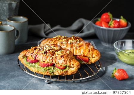 Sweet croissant sandwiches with pistachio cream, strawberries and caramel dip Sweet croissant sandwiches with pistachio cream, strawberries and caramel dip 97857504