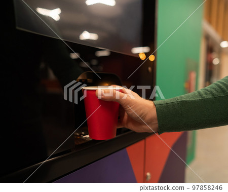 Caucasian man pours himself coffee from a vending machine. Close up. Caucasian man pours himself coffee from a vending machine. Close up. 97858246