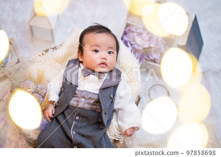 A 3-month-old baby looking at the camera cutely in a tuxedo A 3-month-old baby looking at the camera cutely in a tuxedo 97858698