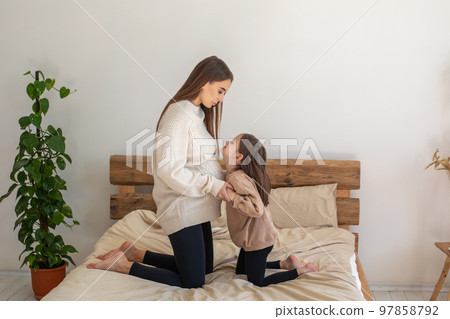 Little girl looking interested while listening to babys moves in her moms belly Little girl looking interested while listening to babys moves in her moms belly 97858792