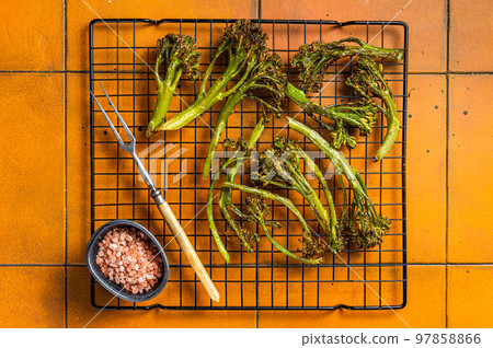 Grilled Broccolini Sprouts with garlic. Orange background. Top view 97858866