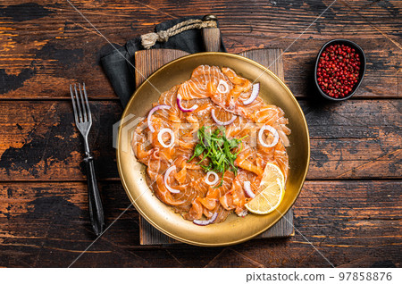 Italian Salmon carpaccio with onion and arugula served on a plate. Wooden background. Top view Italian Salmon carpaccio with onion and arugula served on a plate. Wooden background. Top view 97858876