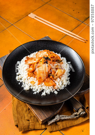 Kimchi with pork on cooked rice, traditional Korean cuisine. Orange background. Top view Kimchi with pork on cooked rice, traditional Korean cuisine. Orange background. Top view 97858887