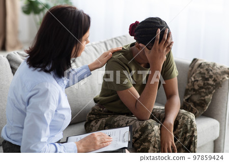 Female Psychologist Comforting Black Soldier Lady During Therapy Session In Office 97859424