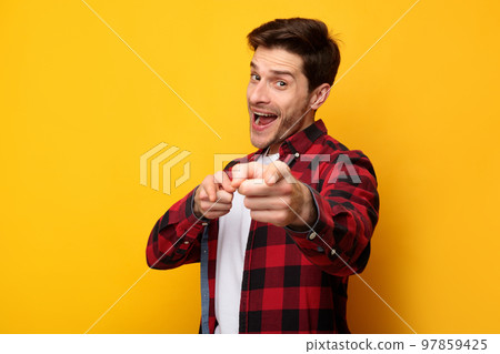 Happy young man pointing fingers at camera at studio 97859425